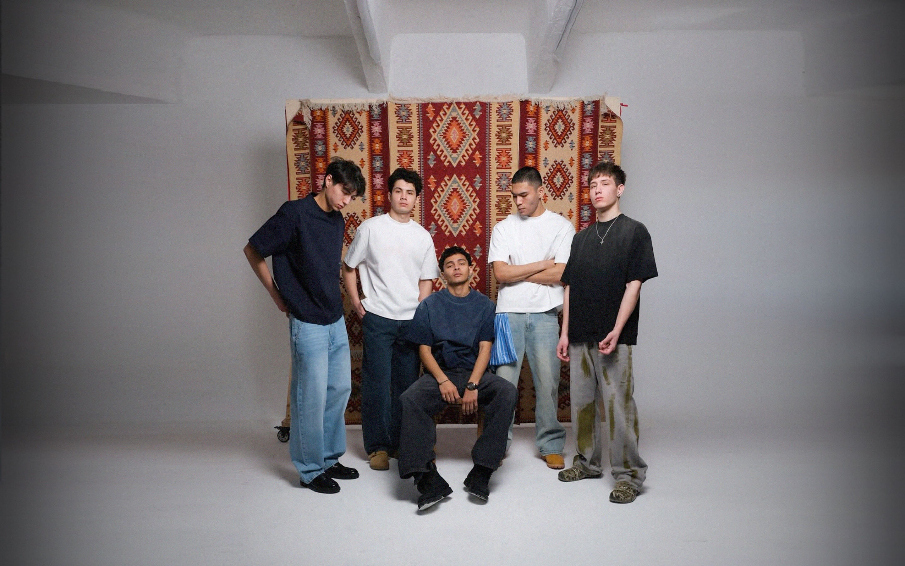 Five men standing in front of a patterned curtain in a our studio setting wearing lorem & ipsum t-shirts